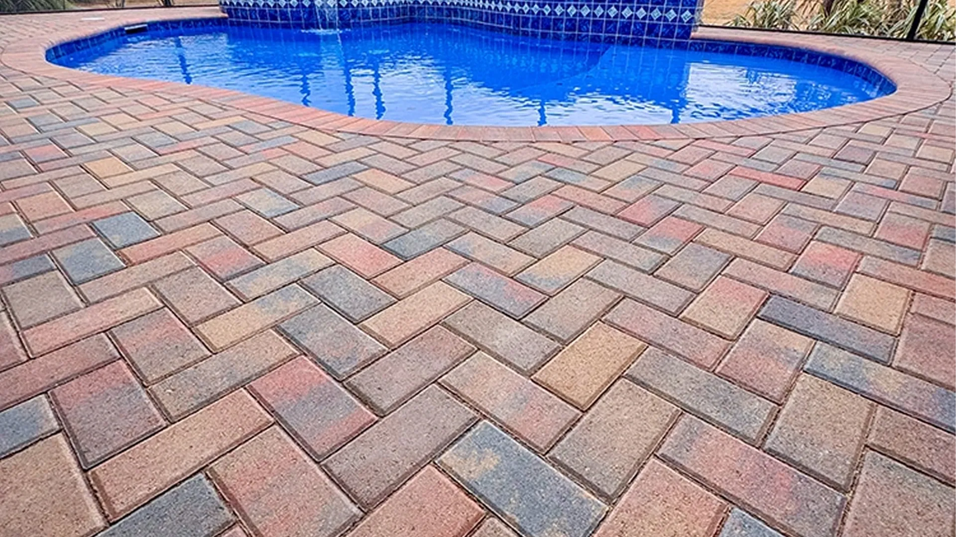 Pool deck paver installation with herringbone pattern around swimming pool Pool deck paver installation with herringbone pattern around swimming pool