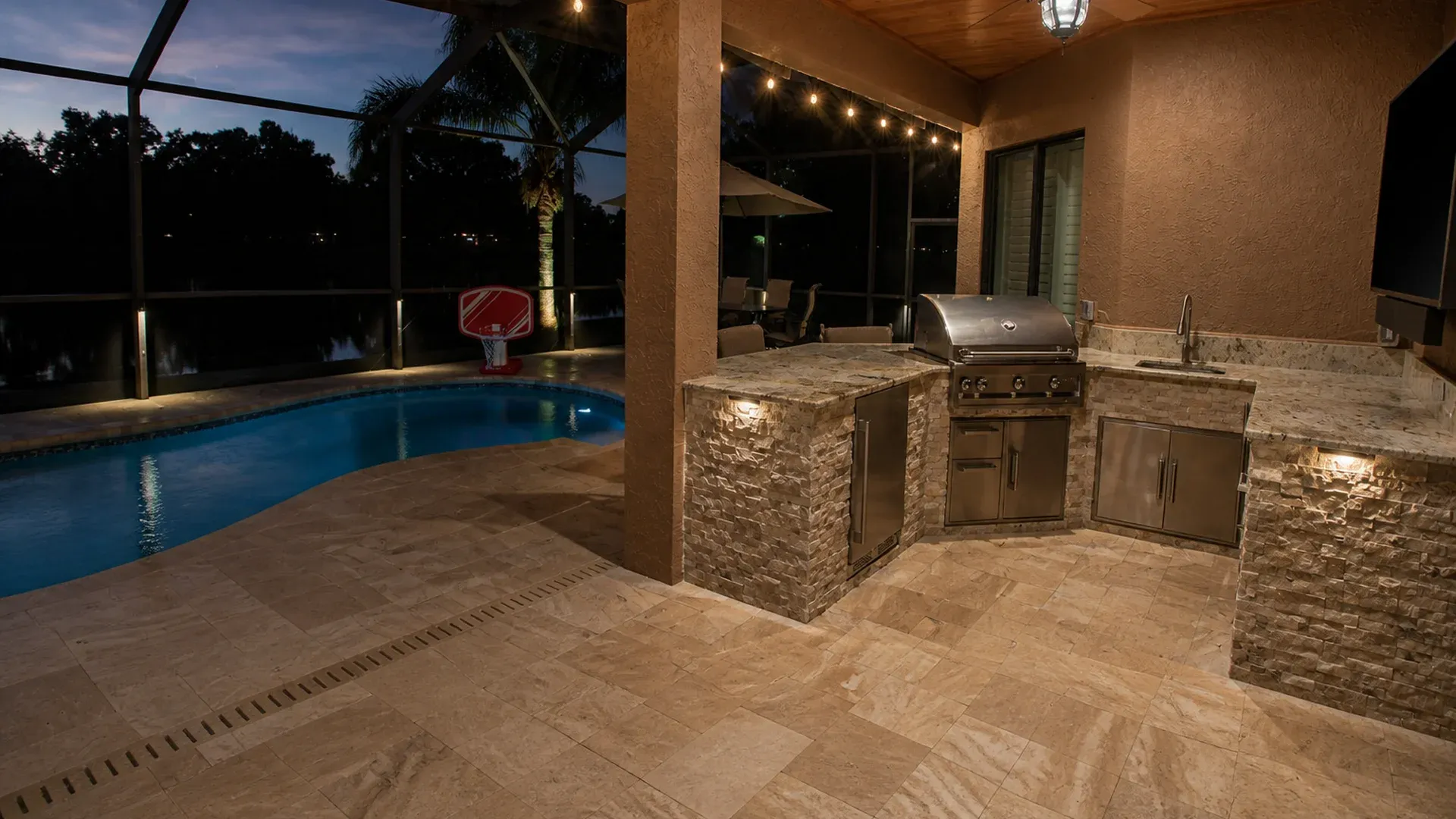 Outdoor kitchen connected to lanai and pool with paver patio in Florida